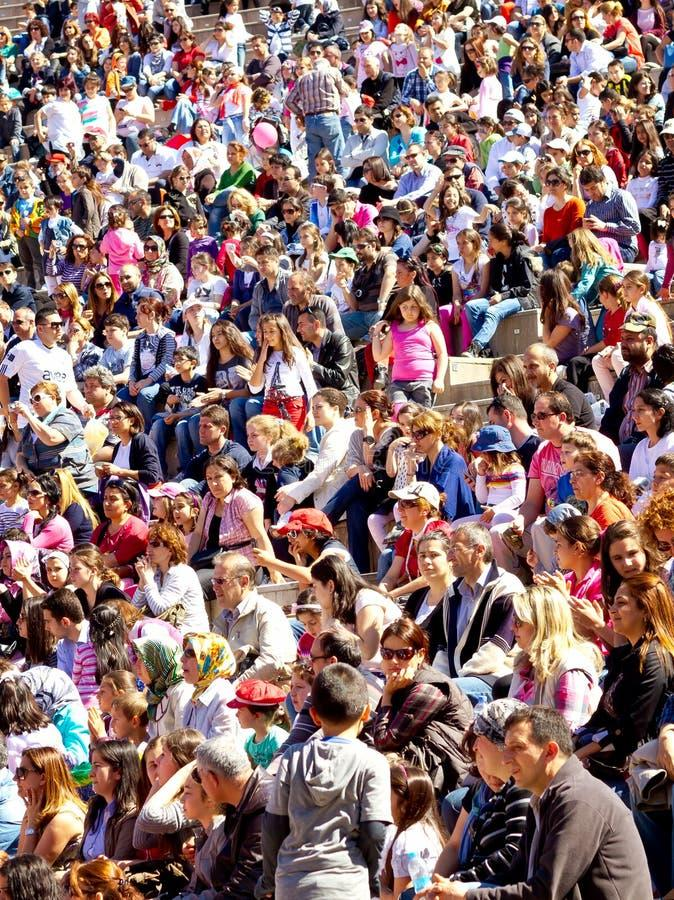 A large crowd of humans sitting close together outdoors.